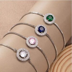 Four elegant bracelets with colored gemstone centers on a wrist.