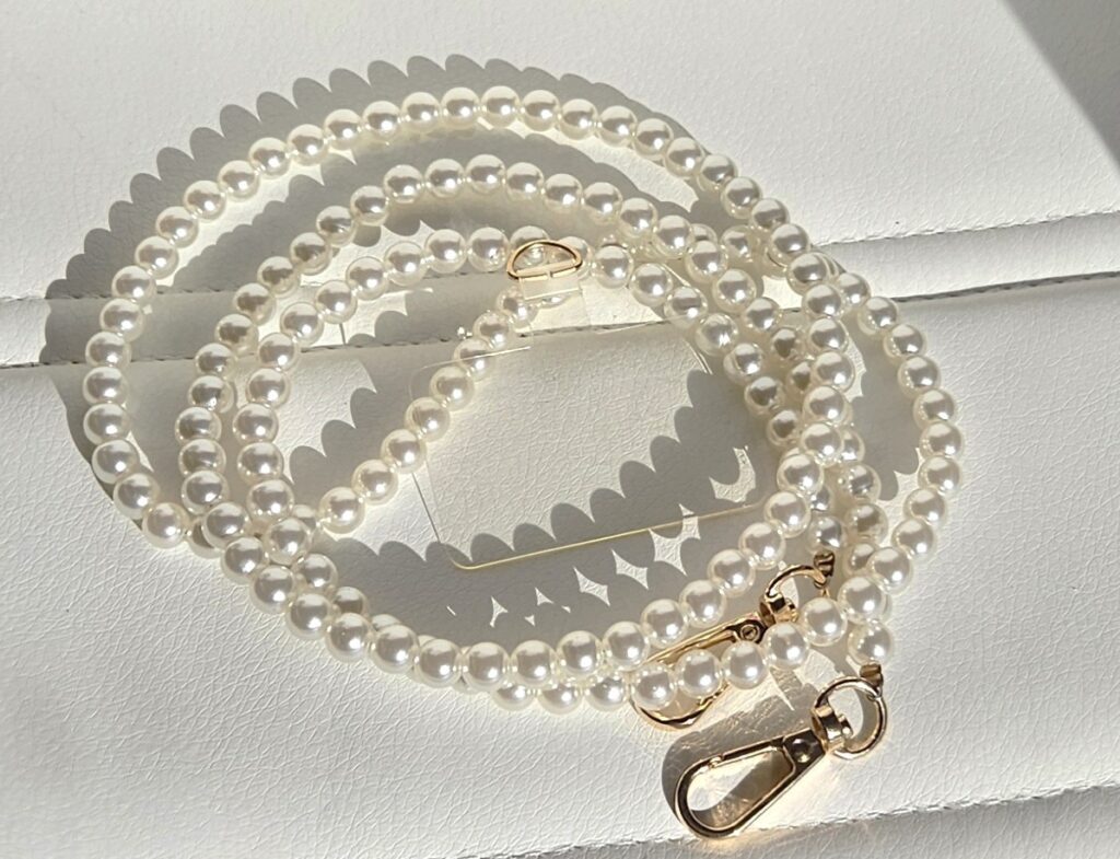 Elegant pearl necklace with a silver clasp casting soft shadows.